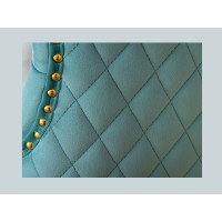 Zoom sur l'aspect matelassé de la chaise REGINA bleu turquoise et dorée avec tête de lion